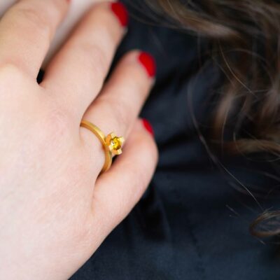 Frau mit roten Nägeln trägt fairtrade Verlobungsring in Gelbgold mit gelbem Fairtrade Saphir von Schmuckdesigner Jan Spille