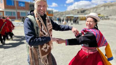 jan spille und peruanische frau tanzen in traditioneller kleidung bei bergbaureise für fairtrade-siegel gold in peru