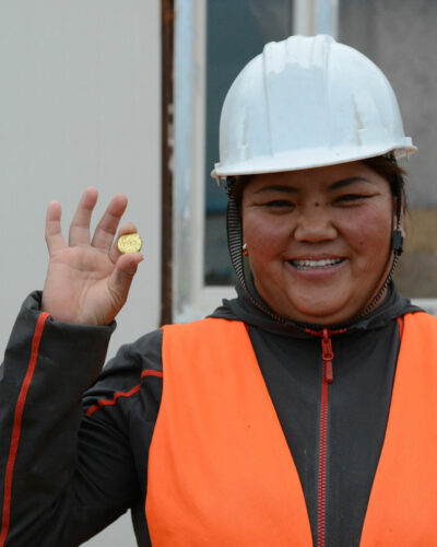 Minenarbeiterin in der Mongolei präsentiert faires, ökologisches Gold als Goldbarren in der Hand