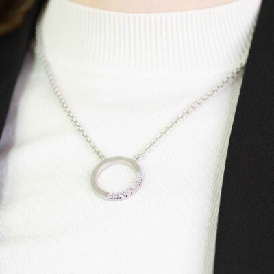 Nahhaufnahme von Frau mit hellem Pullover und rundem Kettenanhänger aus Fairtrade Weißgold der Fischgrätkollektion von Jan Spille mit ethischen Diamanten Fair Trade Schmuck