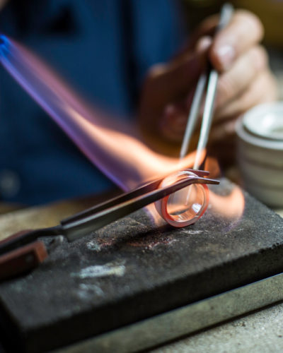 zwei zangen halten eckigen ehering währned eine flamme ihn erhitzt in der jan spille goldschmiede werkstatt hamburg