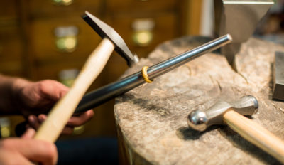 goldener ehering mit hammerschlag in der hertsellung am ringstock in der goldschmiede werkstatt hamburg jan spille