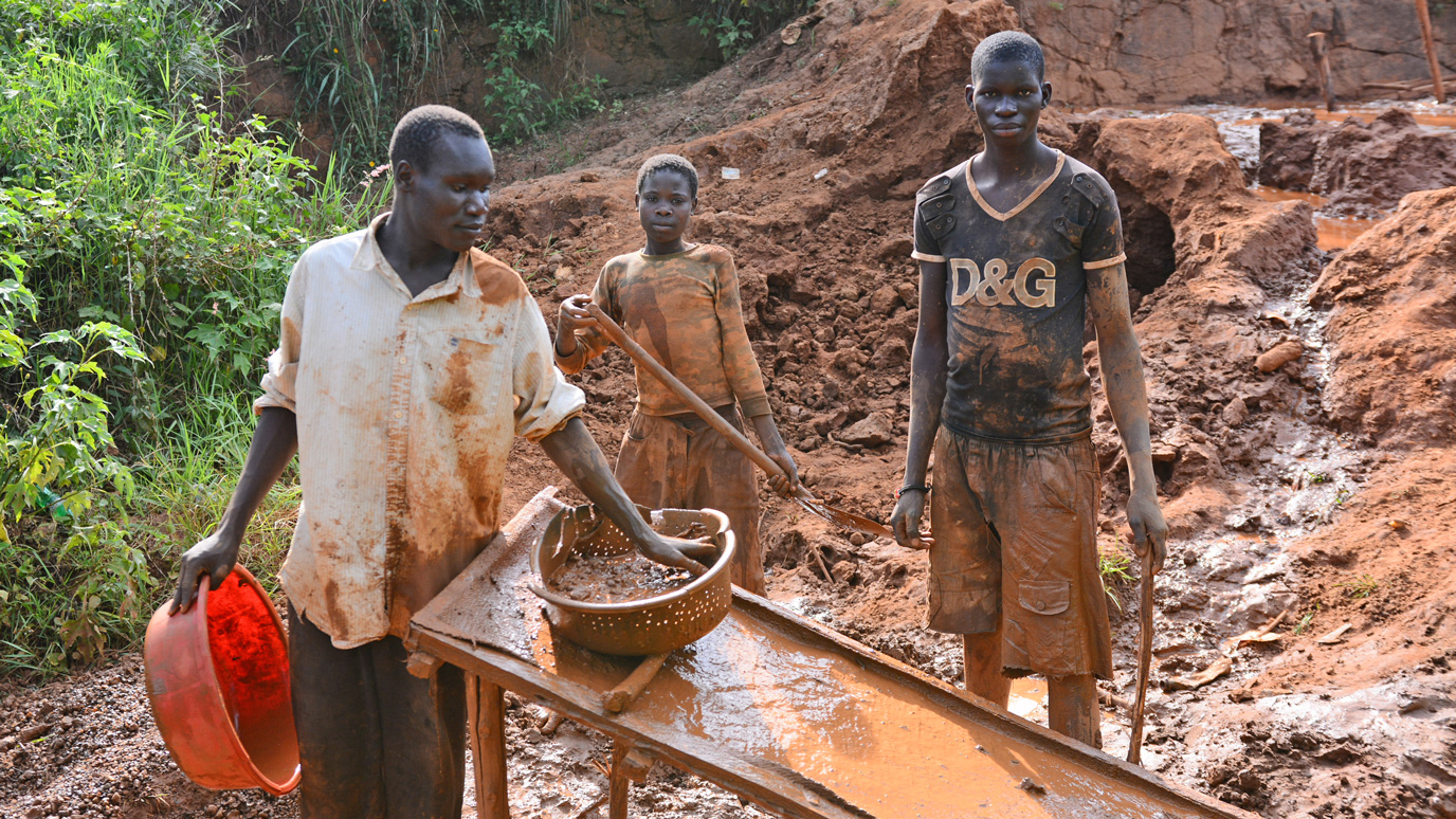 Kinderarbeit im Goldbergabu. Vater mit Kindern beim Goldabbau in Uganda
