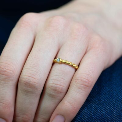 Frau trägt Verlobungsring mit kleinem Stein aus der Kordel-Kollektion von Jan Spille aus Fairmined Eco Gelb Gold mit ethischem Diamanten