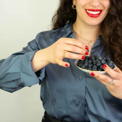Frau zeigt eine Schlüssel mit Blaubeeren und trägt Kugelring, Kettenanhänger mit Kugel und Kugel Creolen aus der Kugel-Kollektion: Schmuck nachhaltig gefertigt von Jan Spille Schmuck Hamburg