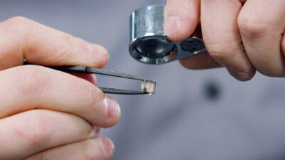 Ein roher Labgrown Diamant wird mit der Lupe untersucht