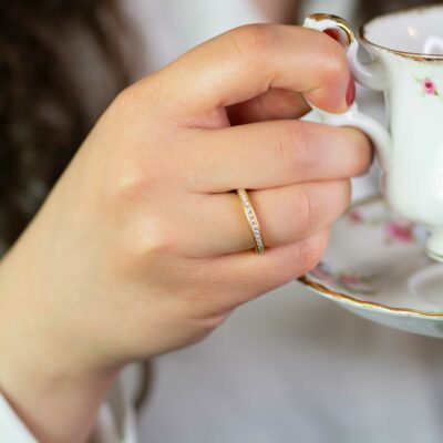 Frau hält Teetasse und trägt klassischen Echtgold Verlobungsring aus Fairtrade Gold im Pavé mit konfliktfreien Naturdiamanten