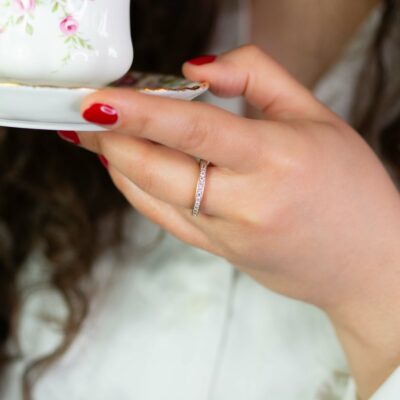 Frau hält Untertasse und trägt klassische Verlobungsringe aus Fairmined Gold im Pavé mit konfliktfreien Naturdiamanten