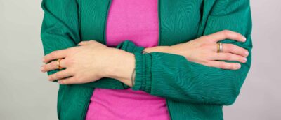 Frau mit grüner Jacke trägt runde Verlobungsringe mit Zargenfassung aus Recycling Gold mit Ethical Diamonds aus Hamburg