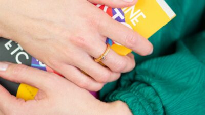 Frau hält Karton und zeigt runden Verlobungsringe mit Zargenfassung aus Recycling Echtgold mit Ethical Diamond von Jan Spille aus Hamburg