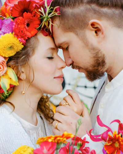 brautpaar mit bunter blumendeko küsst sich und trägt trauringe mit matter oberfläche
