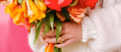 braut hält bunten blumenstrauß und zeigt ehering und verobungsring von jan spille