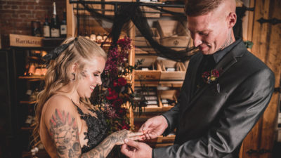 Hochzeit in schwarz: Mann steckt seiner Frau Ehering an den Finger